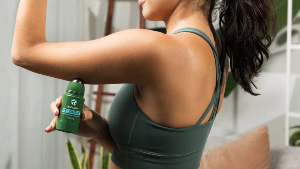 Athlete using Recovery CBD Roll-on to ease tension from muscle pain.