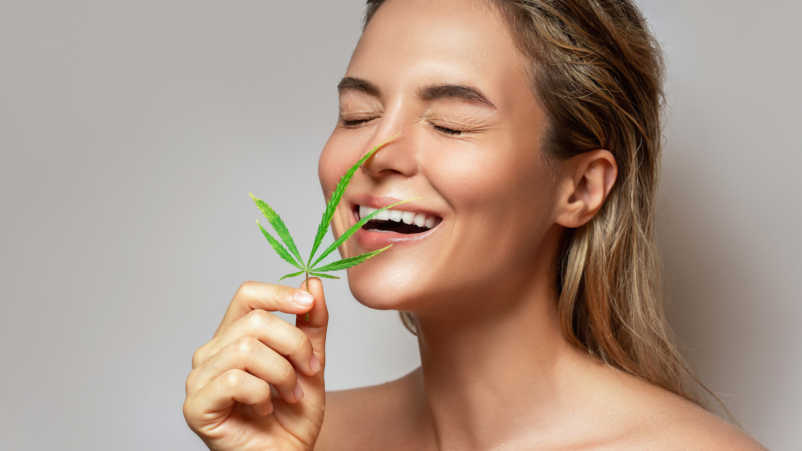 Woman smiling happily with a cannabis leaf.